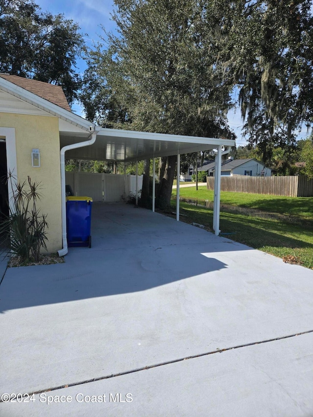 view of car parking featuring a lawn and a carport