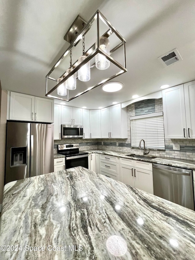 kitchen featuring white cabinetry, appliances with stainless steel finishes, and light stone counters