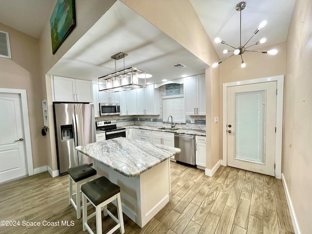 kitchen with white cabinetry, appliances with stainless steel finishes, tasteful backsplash, a center island, and pendant lighting