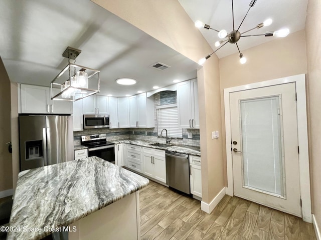 kitchen featuring stainless steel appliances, light stone countertops, hanging light fixtures, and white cabinets