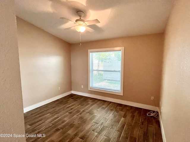 unfurnished room with a textured ceiling, dark wood-type flooring, and ceiling fan