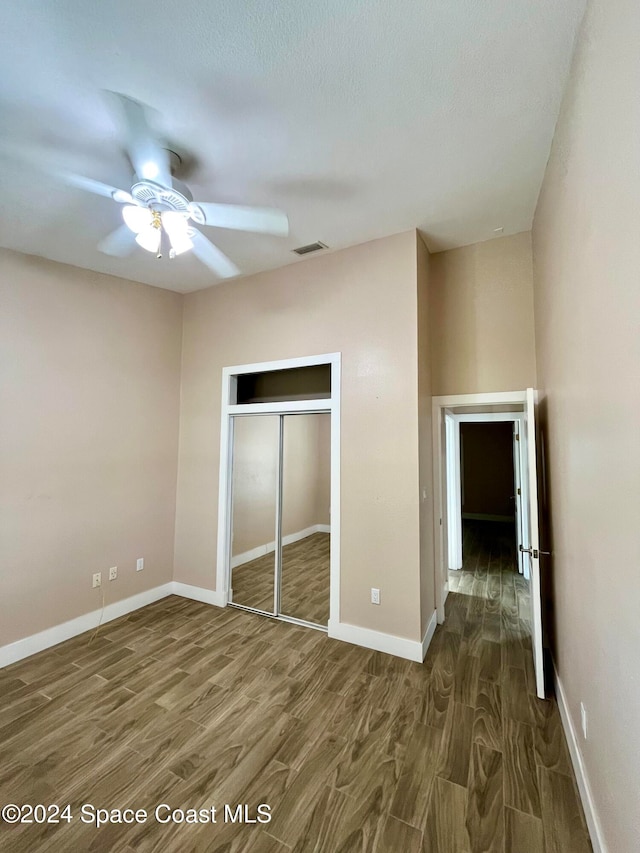 unfurnished bedroom with ceiling fan, a closet, and dark hardwood / wood-style flooring