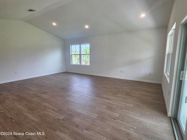 spare room with hardwood / wood-style flooring and vaulted ceiling