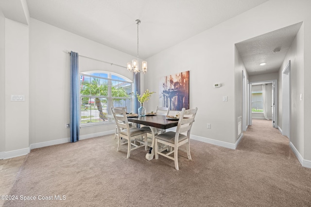 dining area with a textured ceiling, light carpet, and a notable chandelier