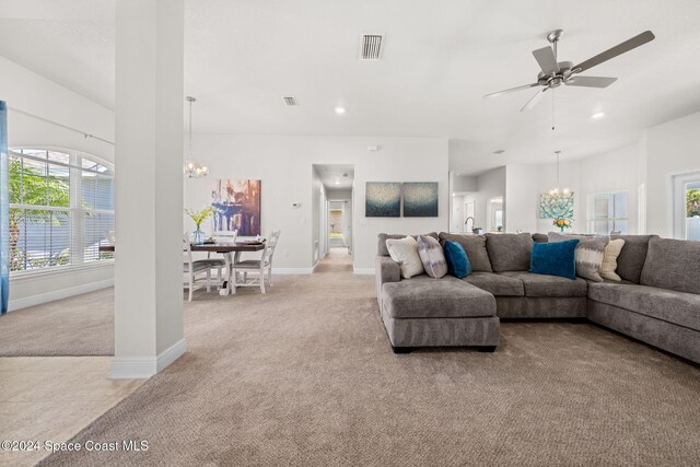 living room featuring light colored carpet and ceiling fan with notable chandelier