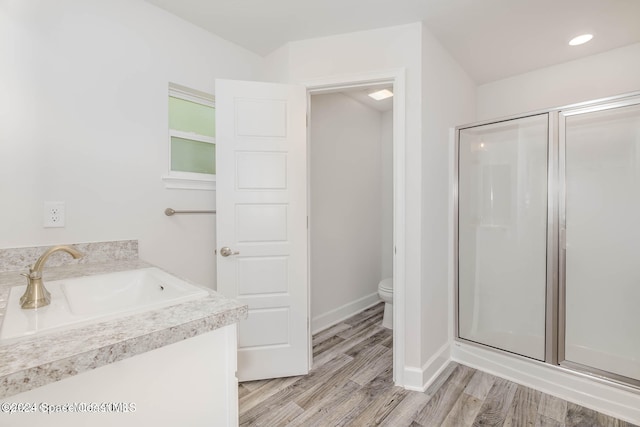 bathroom with wood-type flooring, vanity, a shower with door, and toilet