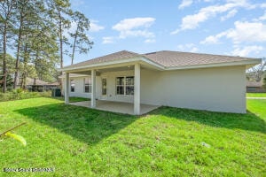 back of house featuring a patio area and a lawn