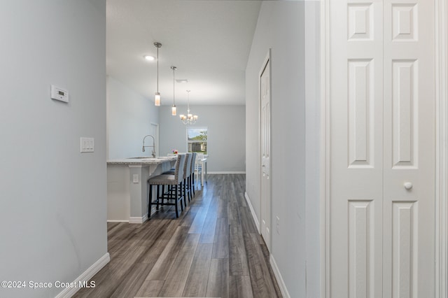 hallway with dark hardwood / wood-style floors, a notable chandelier, and sink