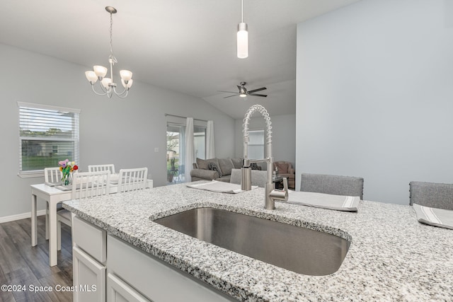 kitchen featuring dark wood-type flooring, ceiling fan with notable chandelier, sink, hanging light fixtures, and vaulted ceiling