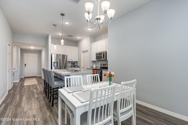 dining area featuring dark hardwood / wood-style flooring, a notable chandelier, and sink