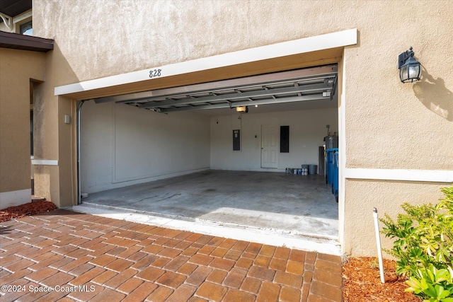 garage with a garage door opener, electric panel, and a carport