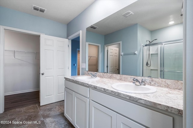 bathroom with a shower with shower door and vanity