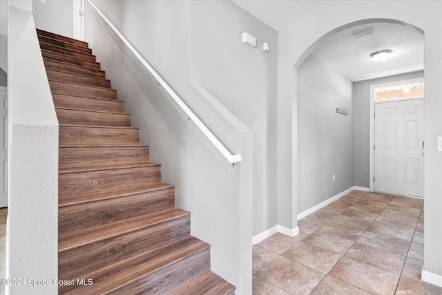 stairs featuring a textured ceiling