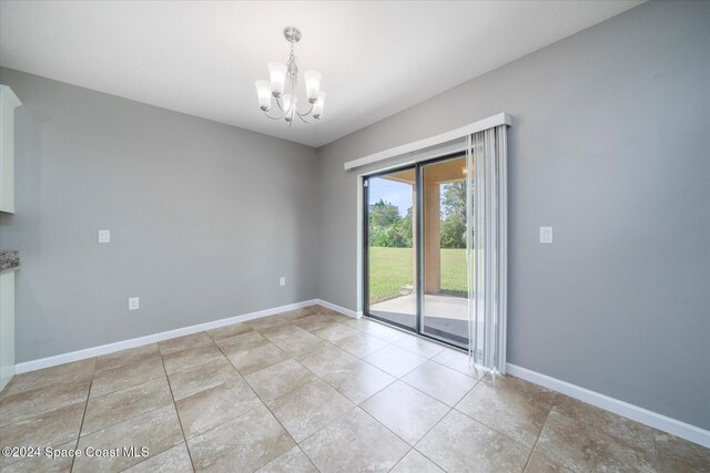 tiled spare room featuring a notable chandelier