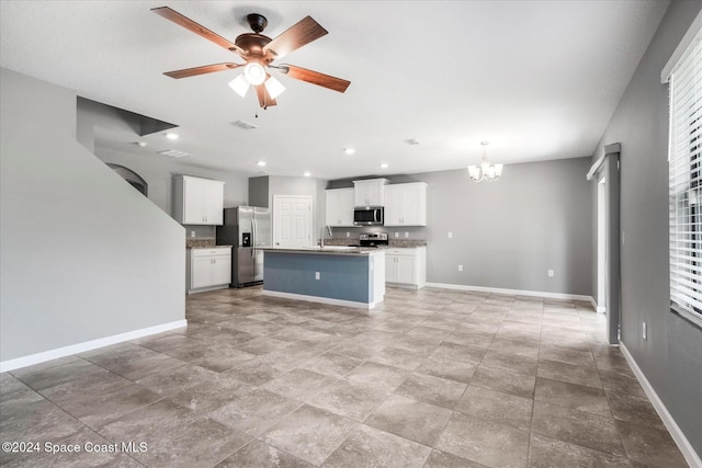 kitchen with stainless steel appliances, a center island with sink, sink, ceiling fan with notable chandelier, and white cabinets