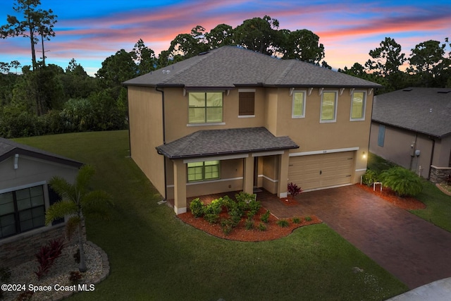 view of front of home with a garage and a lawn