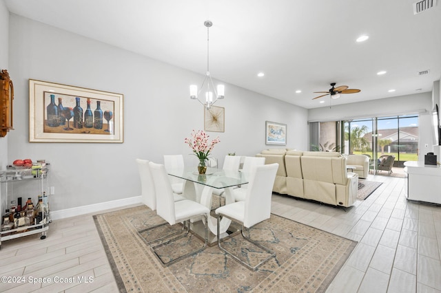 dining area with ceiling fan with notable chandelier and light hardwood / wood-style floors