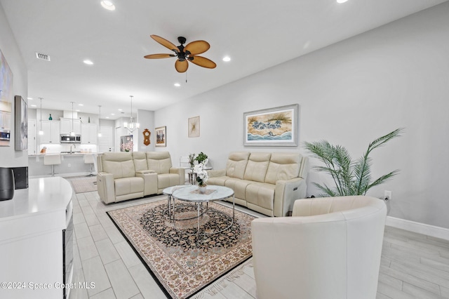 living room with light hardwood / wood-style floors and ceiling fan with notable chandelier