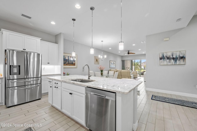 kitchen with white cabinets, stainless steel appliances, a kitchen island with sink, and sink