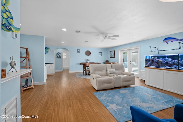 living room featuring ceiling fan, french doors, and light hardwood / wood-style floors