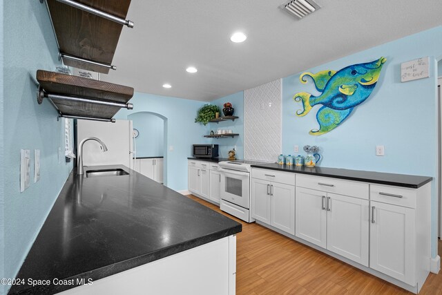 kitchen with electric stove, sink, white cabinets, and light wood-type flooring