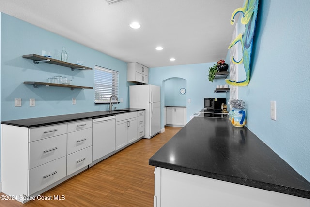 kitchen with white cabinets, light hardwood / wood-style floors, white appliances, and sink