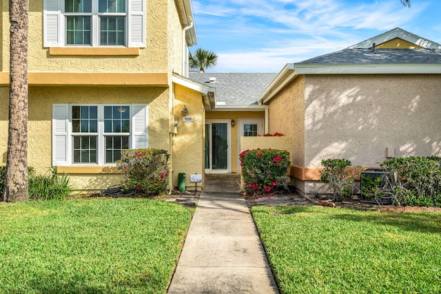 entrance to property featuring a lawn and central AC unit