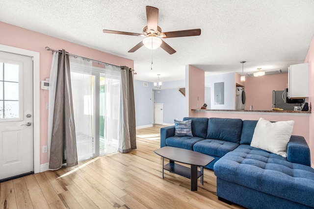 living room with ceiling fan, a textured ceiling, and light wood-type flooring