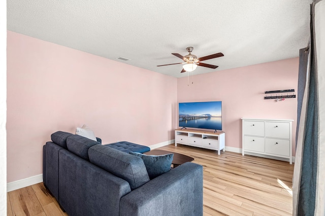 living room featuring ceiling fan, a textured ceiling, and light hardwood / wood-style flooring