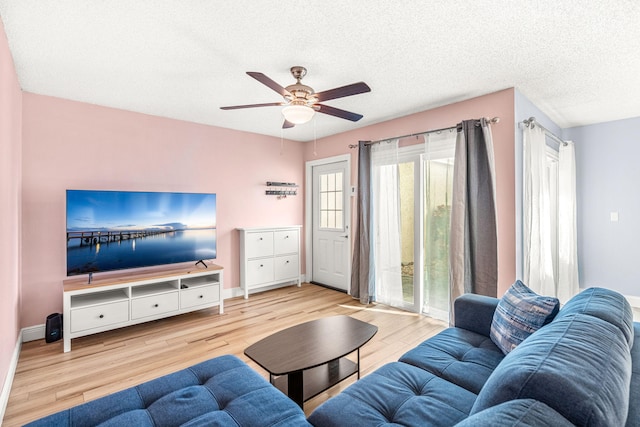 living room with ceiling fan, light hardwood / wood-style floors, and a textured ceiling