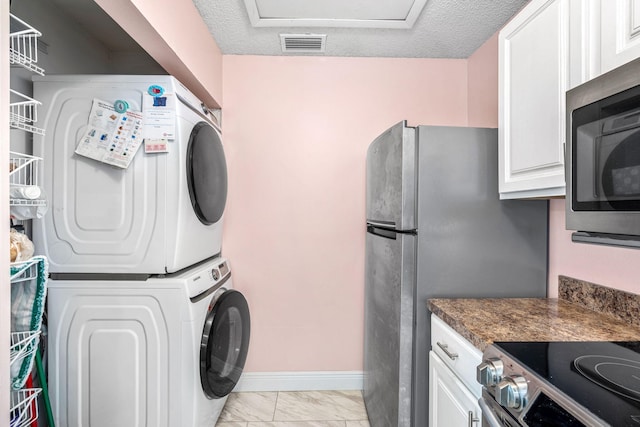 laundry area featuring stacked washing maching and dryer and a textured ceiling