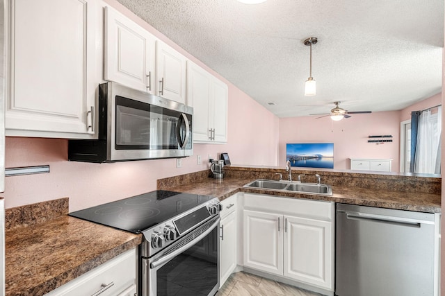 kitchen with appliances with stainless steel finishes, a textured ceiling, ceiling fan, sink, and white cabinetry