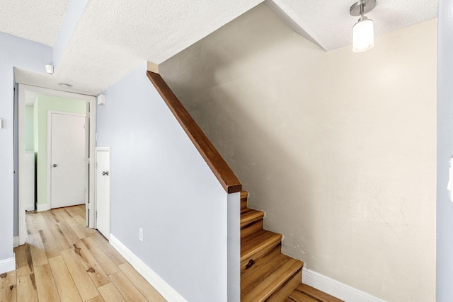 stairway featuring hardwood / wood-style floors and a textured ceiling