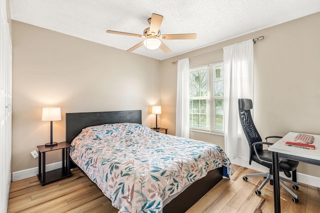 bedroom featuring ceiling fan, light wood-type flooring, and a textured ceiling