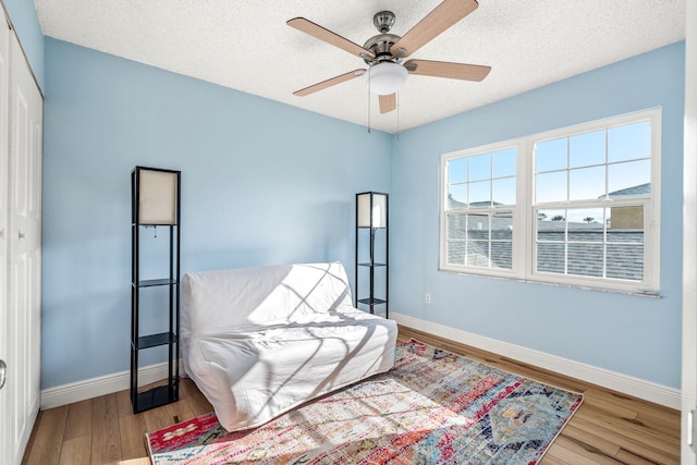 sitting room featuring ceiling fan, a textured ceiling, and light hardwood / wood-style flooring