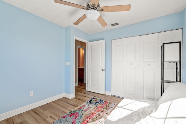 bedroom featuring ceiling fan, light hardwood / wood-style flooring, and a closet