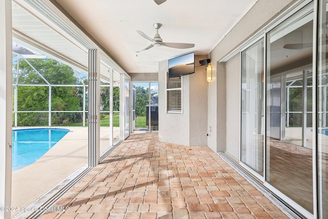 unfurnished sunroom featuring ceiling fan and a pool