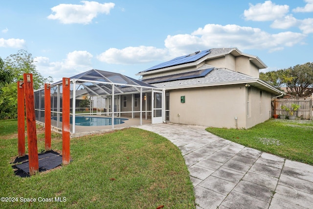 rear view of house featuring a lawn, solar panels, a lanai, and a fenced in pool