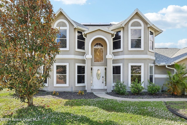 view of front of home featuring solar panels and a front yard