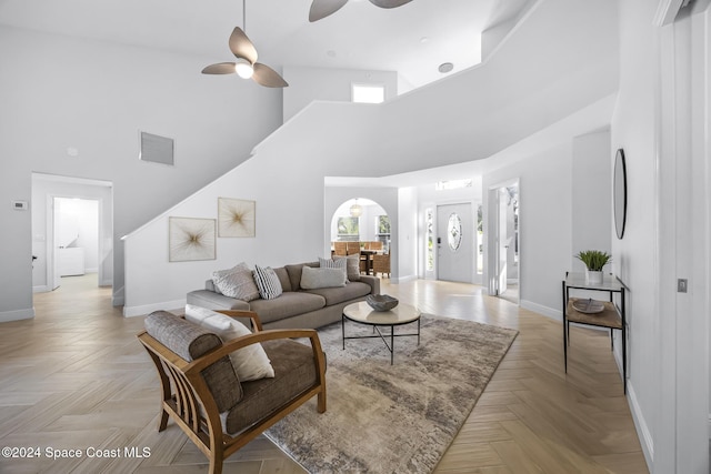 living room featuring ceiling fan, light parquet flooring, and a high ceiling