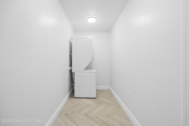 laundry room with stacked washer and dryer and light parquet floors