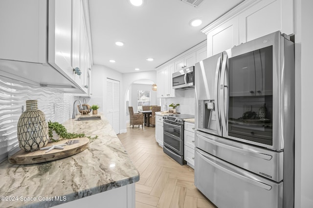 kitchen featuring appliances with stainless steel finishes, tasteful backsplash, and white cabinetry