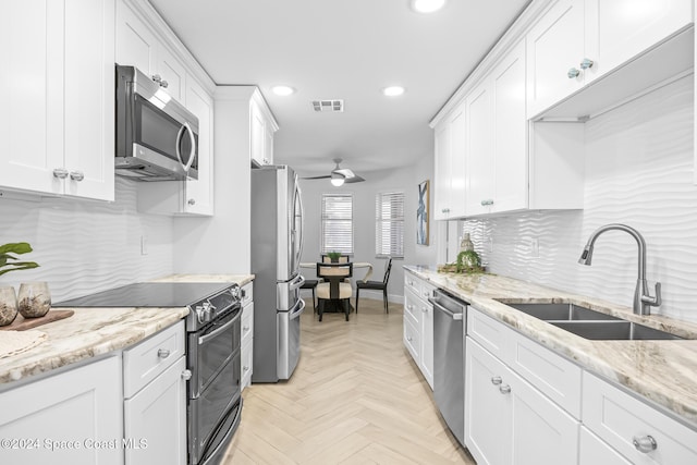 kitchen featuring decorative backsplash, stainless steel appliances, ceiling fan, sink, and white cabinets