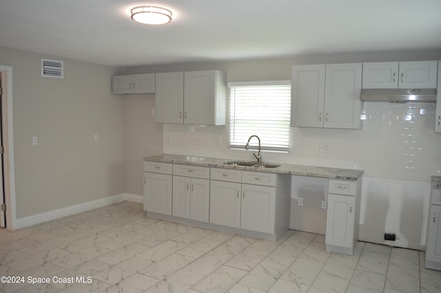 kitchen featuring white cabinetry, sink, light stone counters, and backsplash