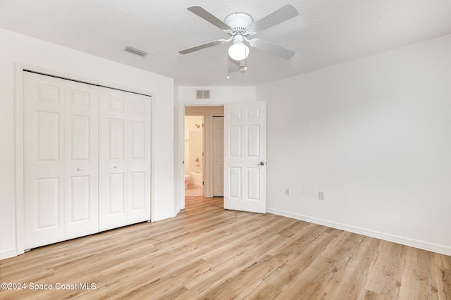 unfurnished bedroom with ceiling fan, a textured ceiling, a closet, and light wood-type flooring