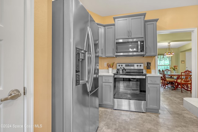 kitchen with light tile patterned flooring, appliances with stainless steel finishes, and gray cabinetry