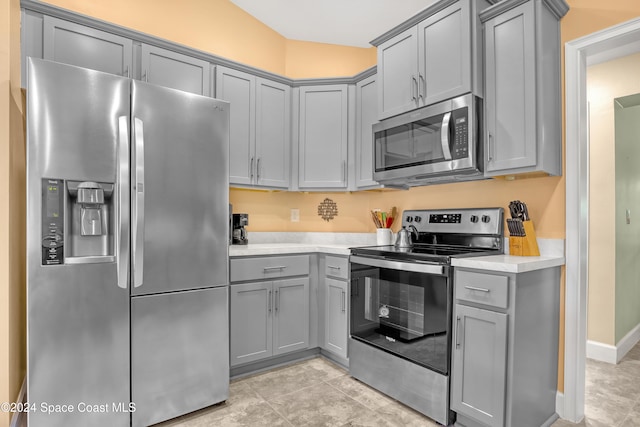 kitchen with light tile patterned floors, appliances with stainless steel finishes, and gray cabinets