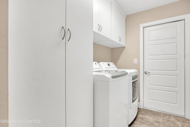 clothes washing area with washer and dryer and cabinets