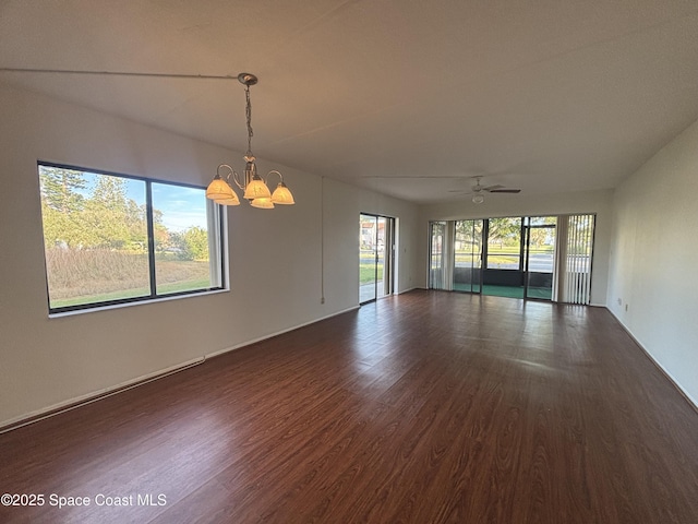 spare room with plenty of natural light, dark hardwood / wood-style floors, and ceiling fan with notable chandelier