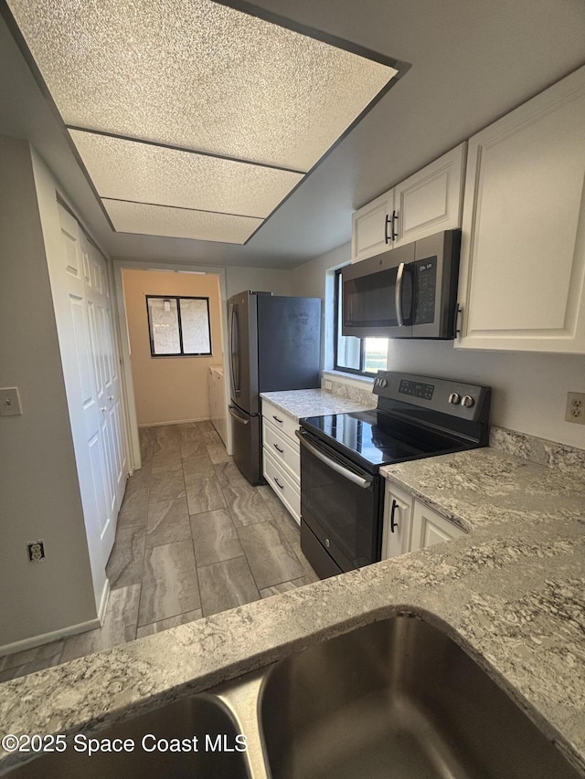 kitchen featuring stainless steel appliances, light stone countertops, and white cabinets